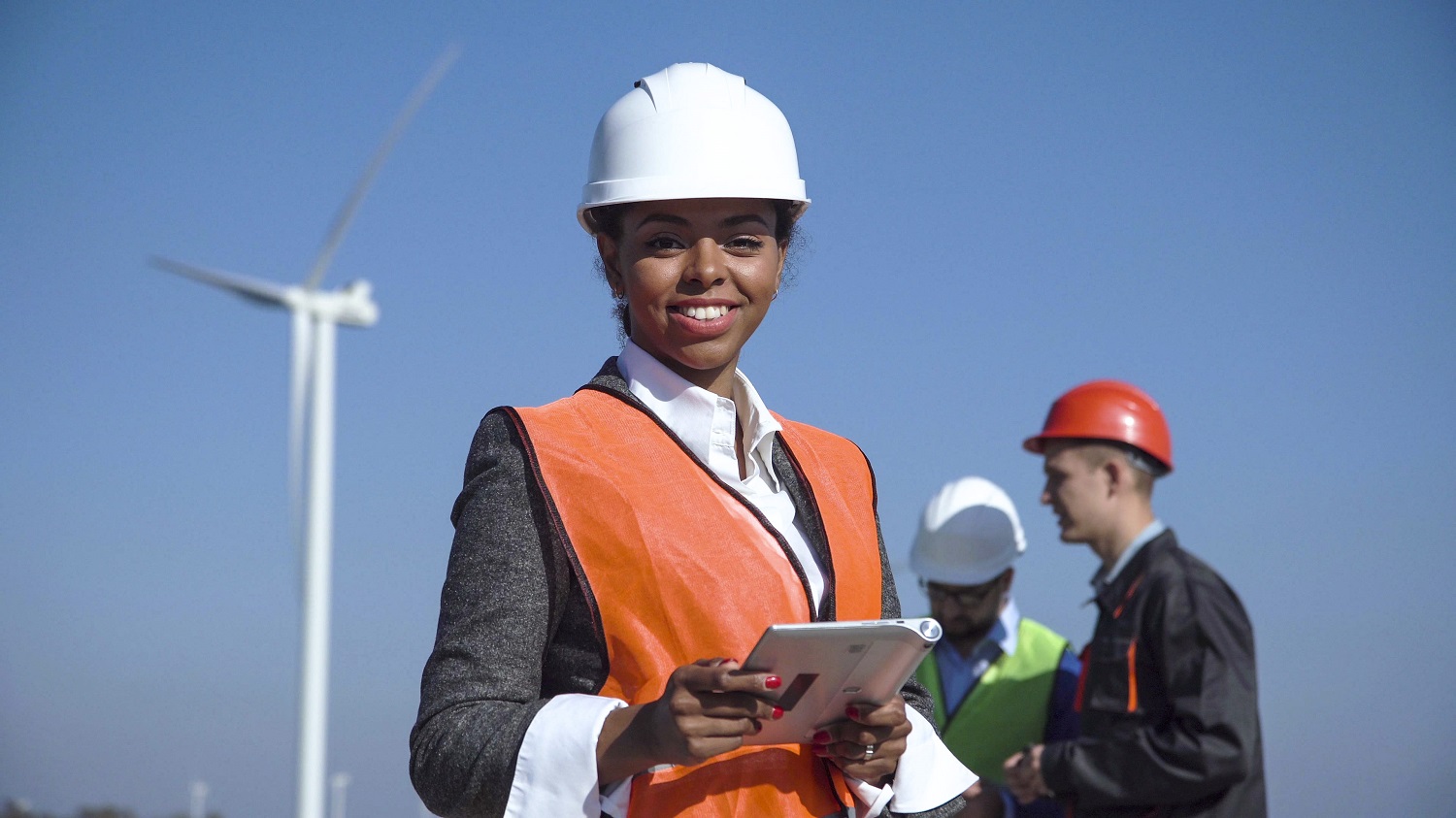 Woman with protective helmet against wind turbine 