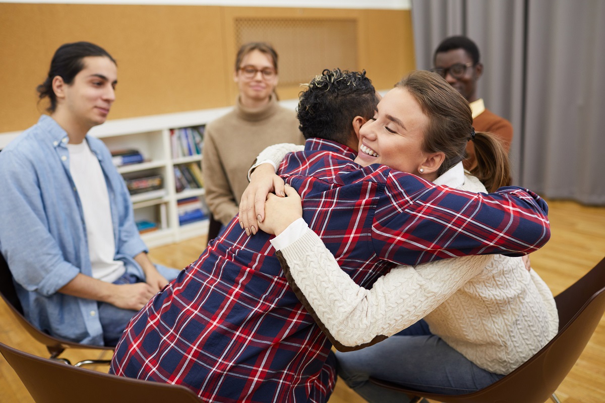 Two youth hugging in support group meeting