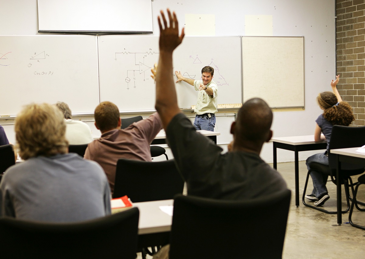 adult student in classroom with hand raised
