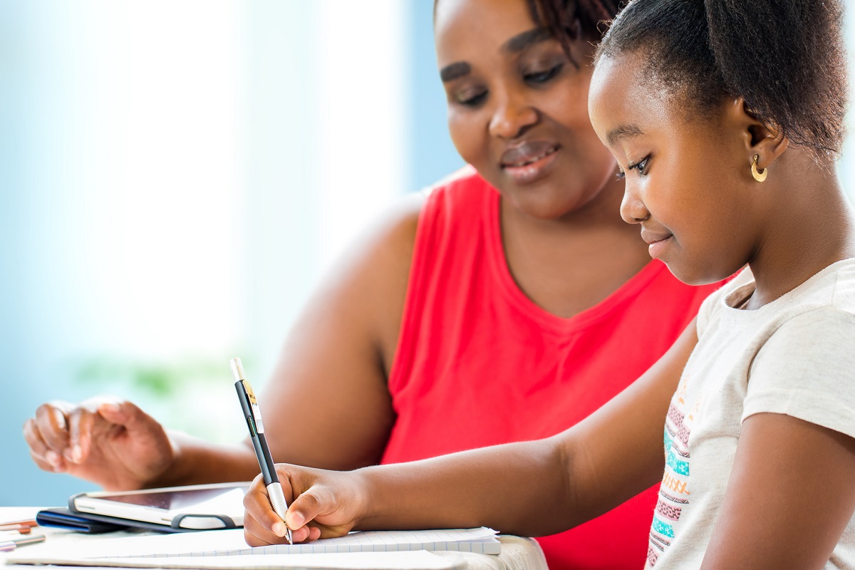Young girl doing homework with mother
