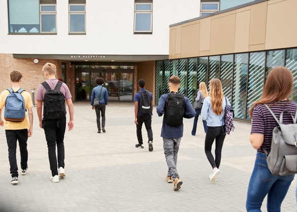 Rear view of high school students walking into a building