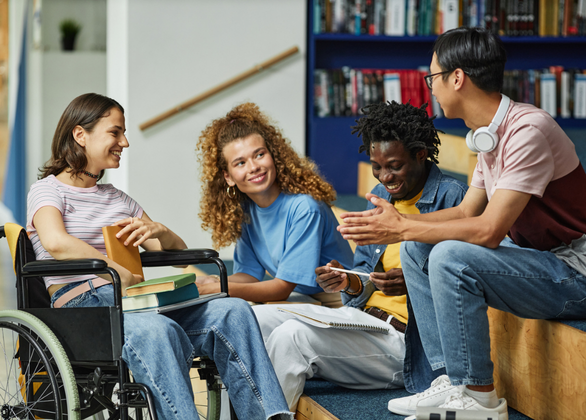 Four young adults speaking to each other in a library
