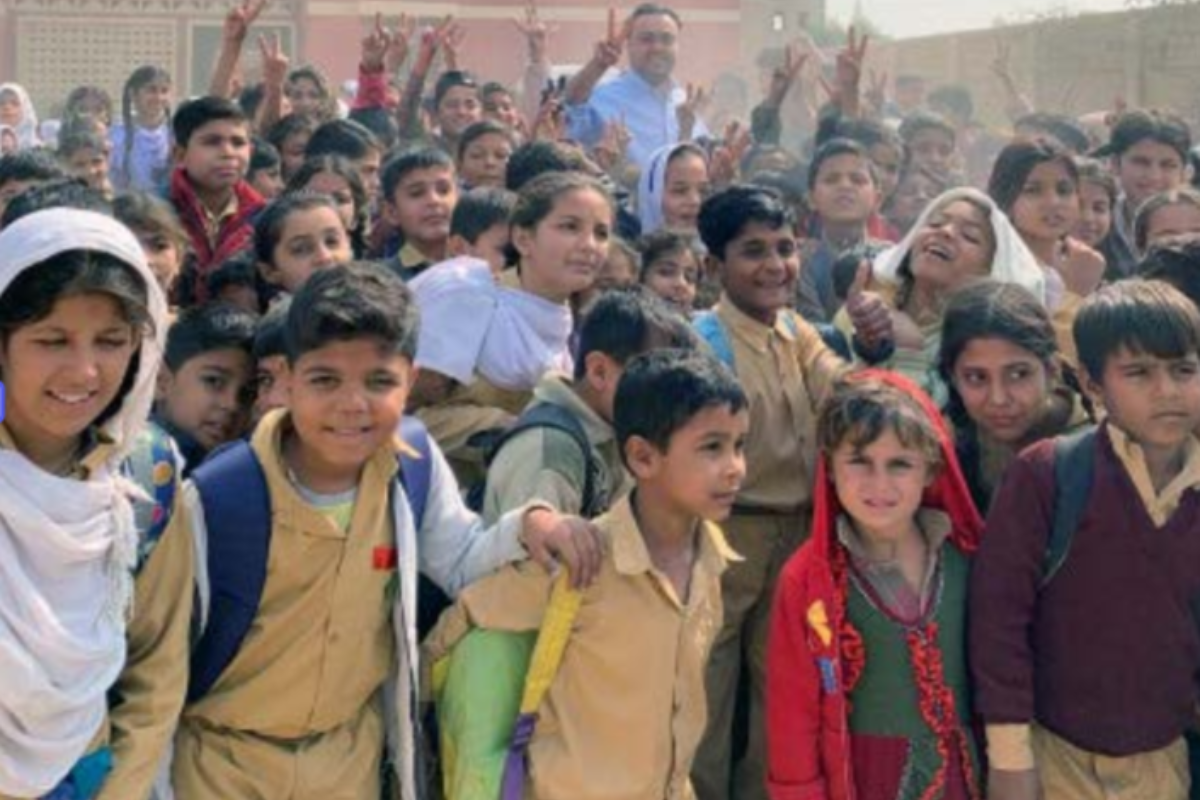 Large group of schoolchildren outdoors, some flashing a peace symbol.