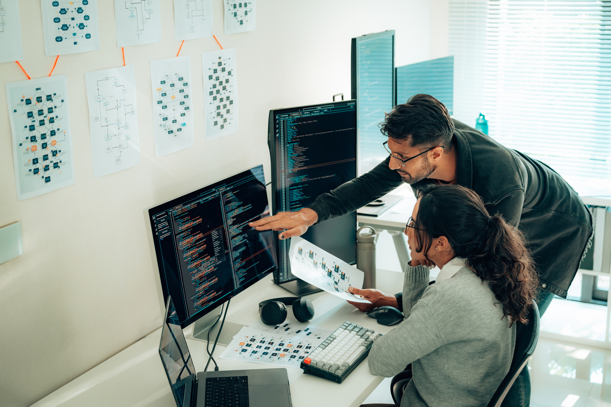 Developers discussing a project in front of a monitor with code on it