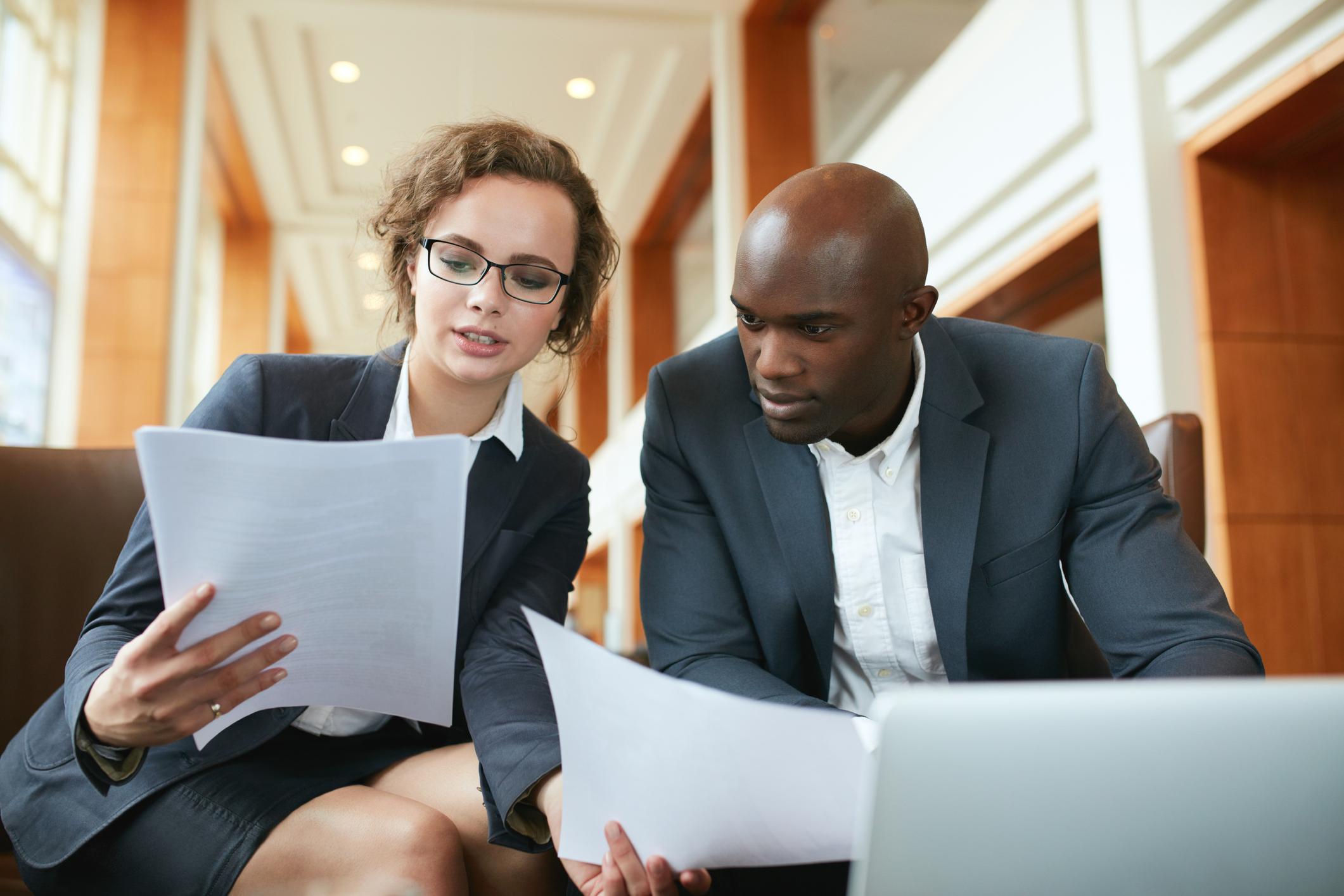 Two business partners sitting in café discussing contract.