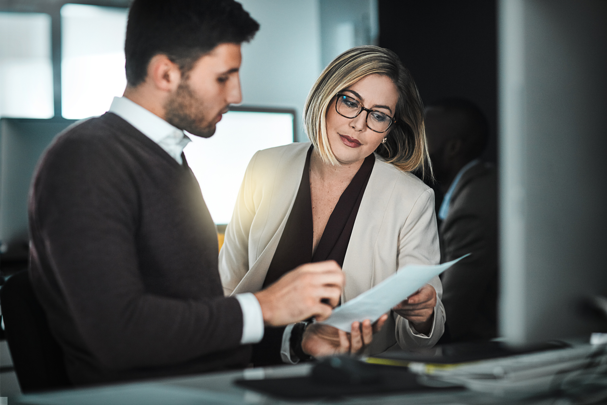A man and a woman in an office discussing a document.