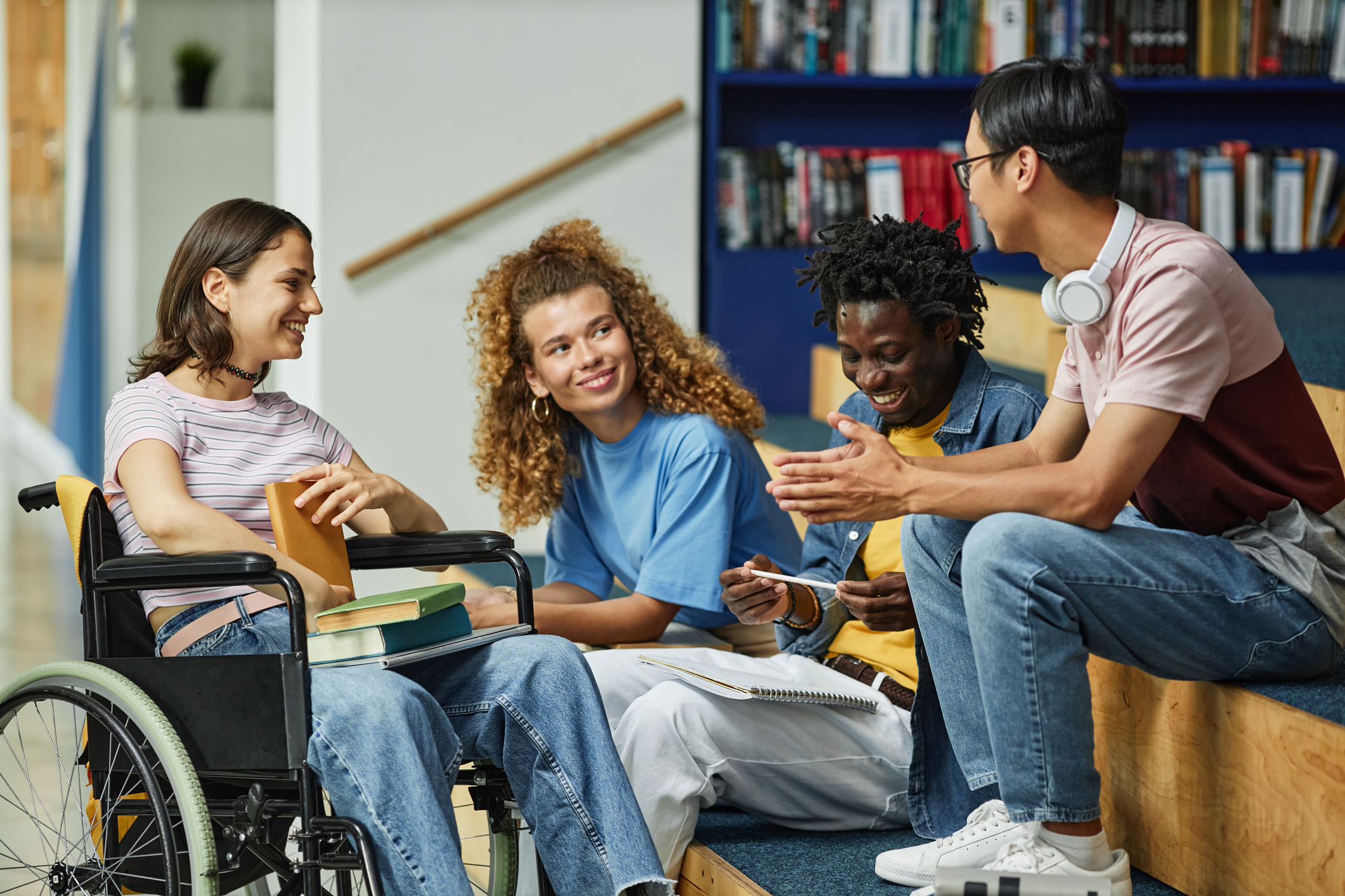 Four young adults speaking to each other in a library