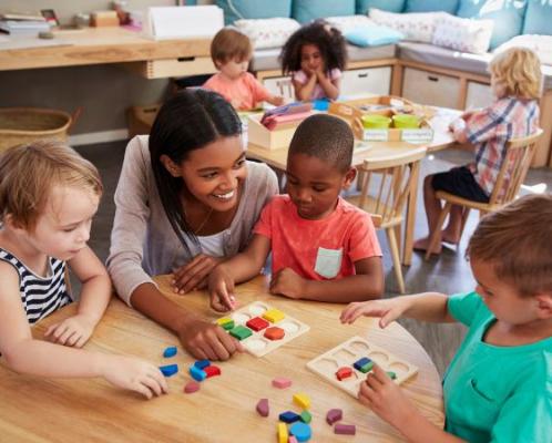 Teacher with preschool students at a desk