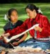 Native American woman teaches weaving to a young girl