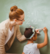 Teacher helps female student with math at blackboard