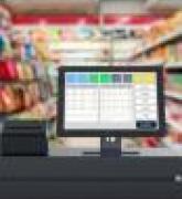 Closeup of cash register with grocery store aisles in background