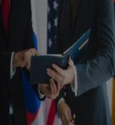 Business leaders sign document with American flag in background