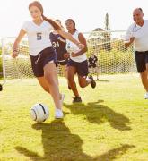 girls playing soccer in field