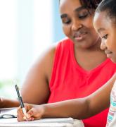 Young girl doing homework with mother