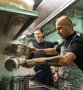 chef teaching his assistant how to cook in a restaurant kitchen