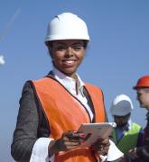 Woman with protective helmet against wind turbine 