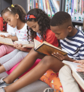 School kids sitting on cushions and studying over books in a library