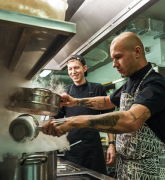 chef teaching his assistant how to cook in a restaurant kitchen