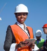 Woman with protective helmet against wind turbine 