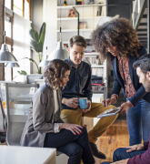 Four office workers looking at a tablet