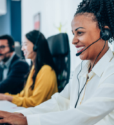 Woman at a call center wearing a headset. Others in background.
