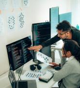 Developers discussing a project in front of a monitor with code on it