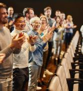 People standing and applauding in an auditorium