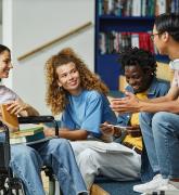 Four young adults speaking to each other in a library